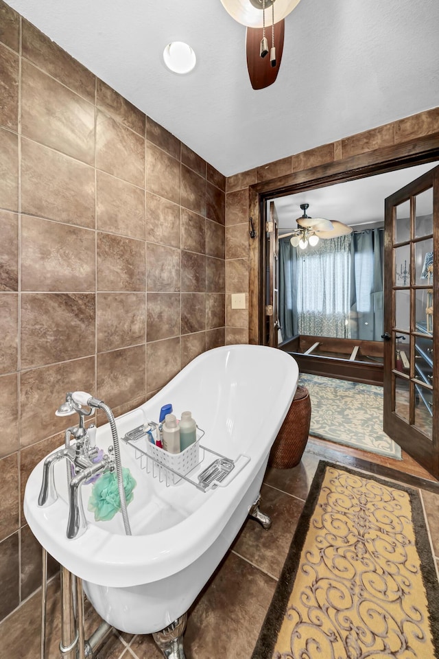 bathroom with tile walls, tile patterned flooring, a tub, and ceiling fan