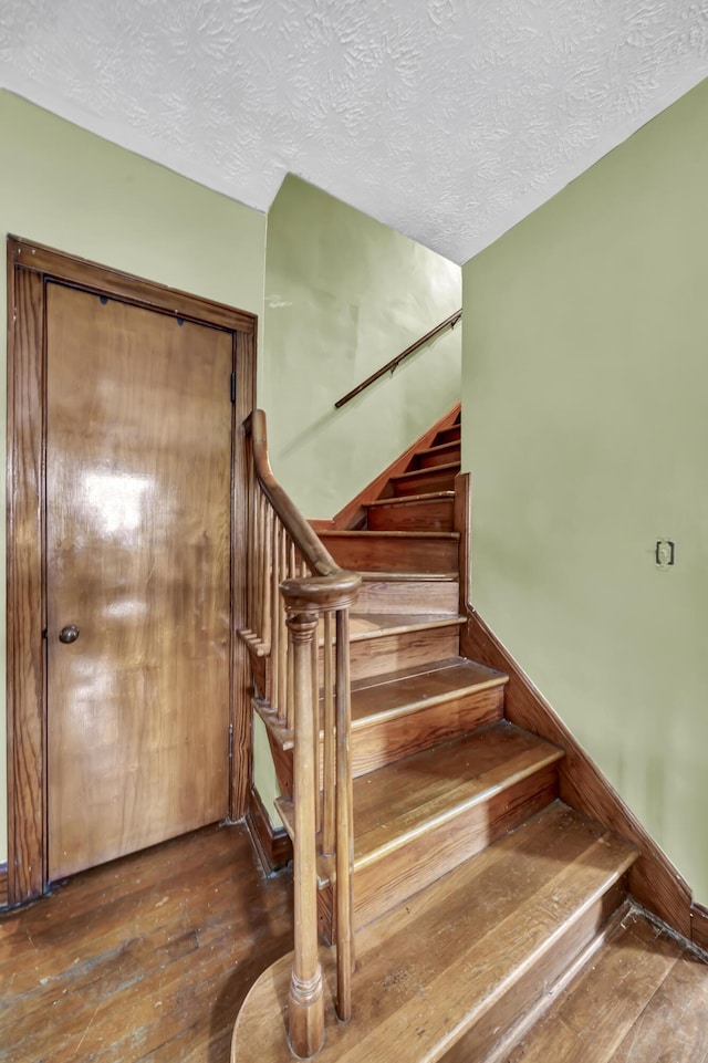 stairway featuring hardwood / wood-style flooring and a textured ceiling