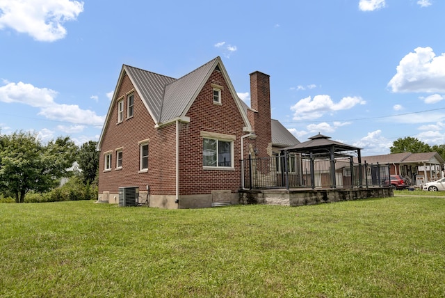 rear view of property featuring a gazebo, central AC unit, and a lawn