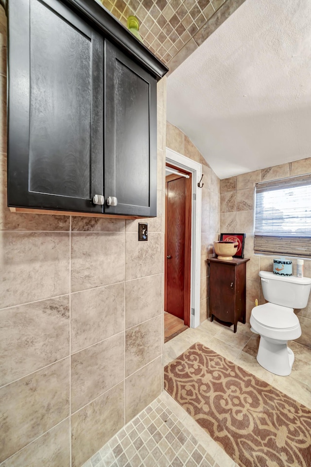 bathroom featuring tile walls, tile patterned flooring, a textured ceiling, vaulted ceiling, and toilet