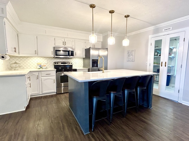 kitchen with sink, a center island with sink, appliances with stainless steel finishes, pendant lighting, and white cabinets