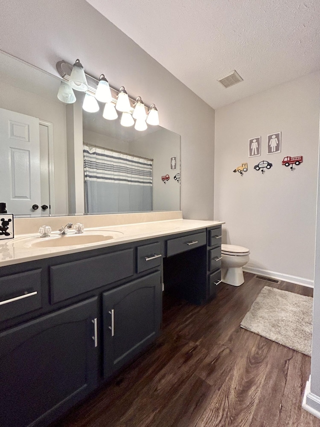 bathroom with vanity, wood-type flooring, toilet, and a textured ceiling