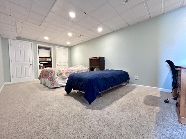 carpeted bedroom featuring a drop ceiling