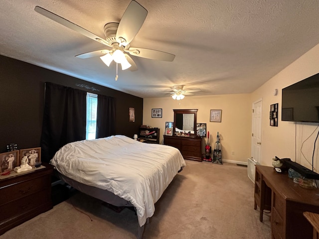 bedroom with ceiling fan, light colored carpet, and a textured ceiling