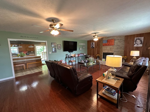 living room with hardwood / wood-style floors, ceiling fan, a fireplace, and a textured ceiling