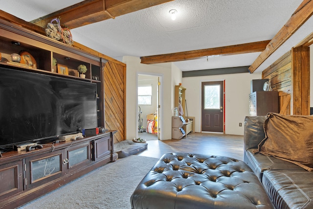 living room with beamed ceiling, a textured ceiling, and hardwood / wood-style flooring