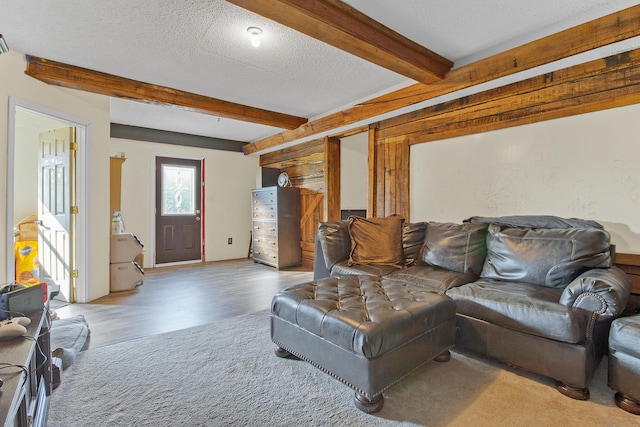 living room with wood-type flooring, a textured ceiling, and beam ceiling