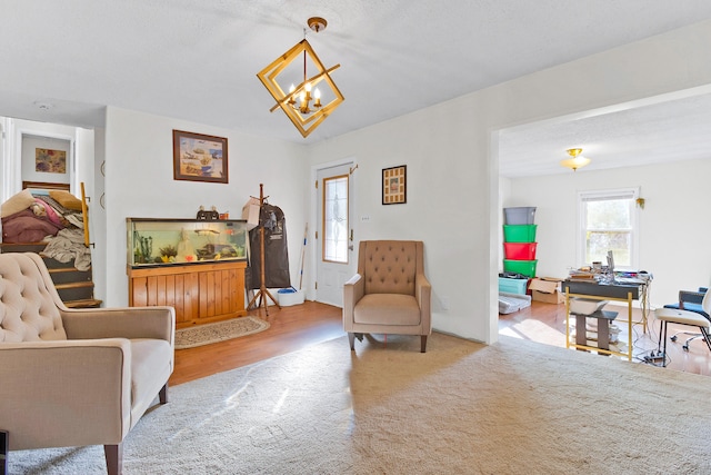 living area featuring light wood-type flooring, a wealth of natural light, a chandelier, and a textured ceiling