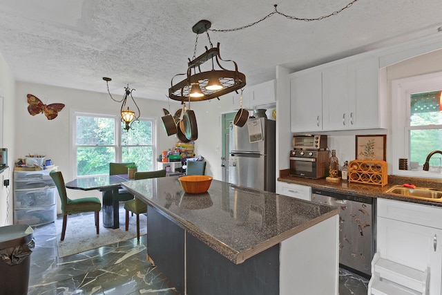 kitchen featuring white cabinetry, appliances with stainless steel finishes, a kitchen island, pendant lighting, and sink