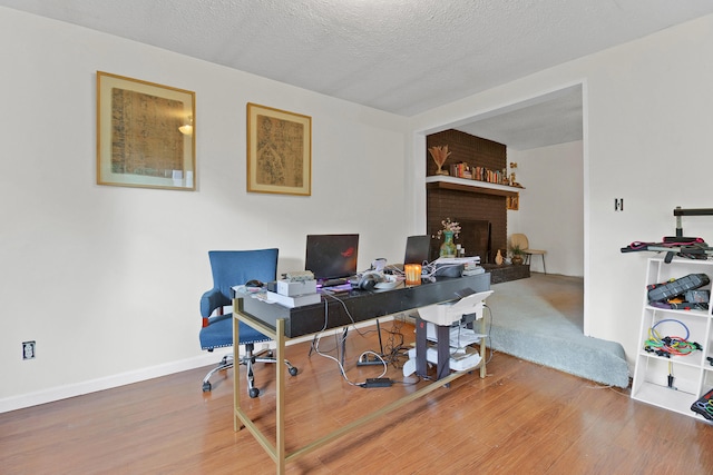 home office with a textured ceiling, a fireplace, and hardwood / wood-style floors