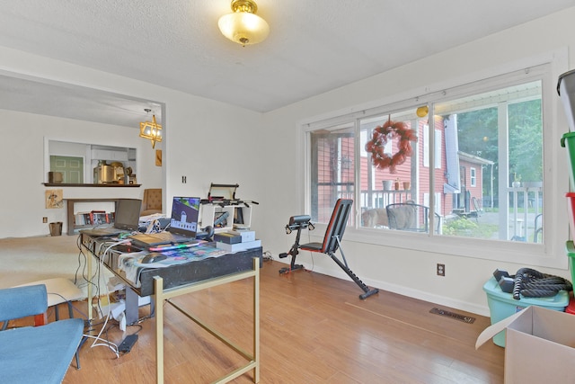 office with a textured ceiling, a wealth of natural light, wood-type flooring, and a notable chandelier