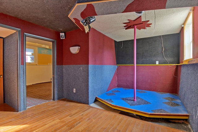 rec room with hardwood / wood-style floors and a textured ceiling