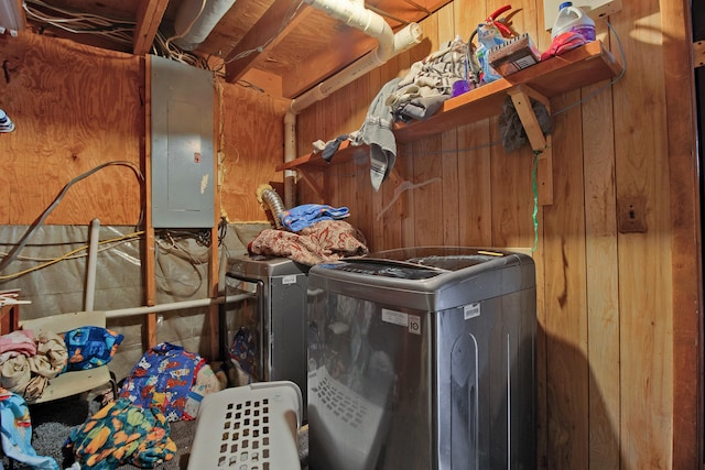 laundry area with washing machine and dryer, electric panel, and wooden walls