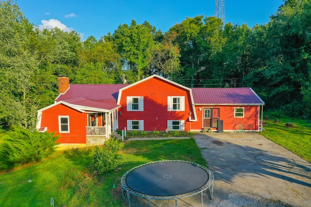 back of property with a lawn, a trampoline, and a porch