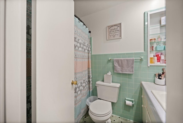 bathroom featuring vanity, tile walls, and toilet