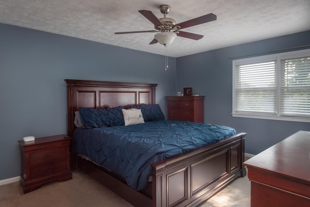 carpeted bedroom featuring ceiling fan and a textured ceiling