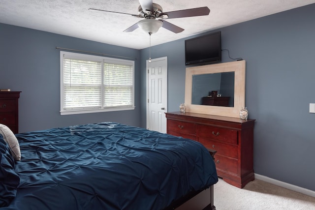 carpeted bedroom with ceiling fan and a textured ceiling