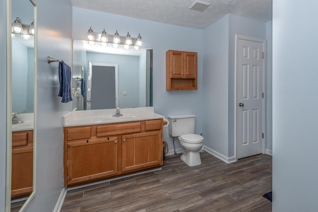 bathroom with vanity, toilet, hardwood / wood-style floors, and a textured ceiling