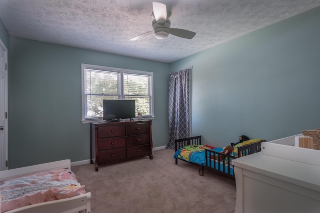 bedroom with ceiling fan, light colored carpet, and a textured ceiling