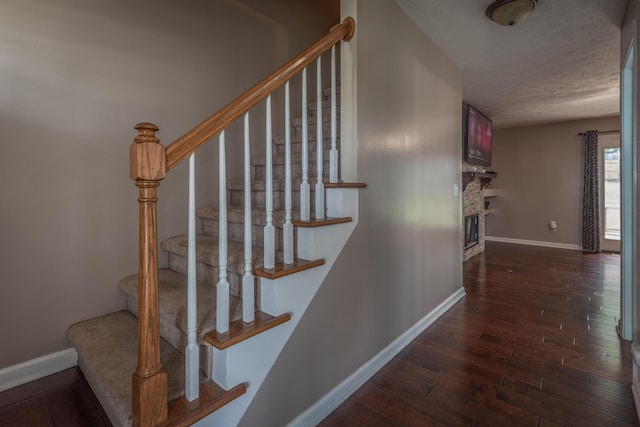 stairs featuring hardwood / wood-style flooring, a fireplace, and a textured ceiling