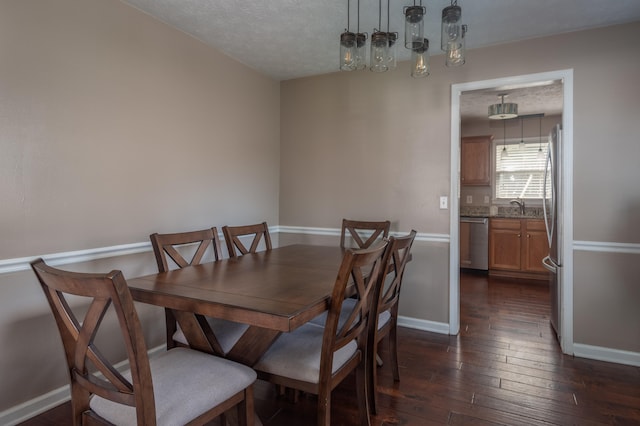 dining area featuring sink, a textured ceiling, and dark hardwood / wood-style flooring