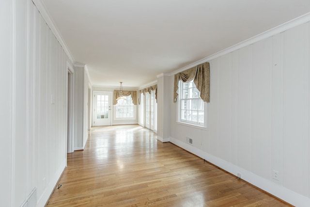 empty room featuring crown molding, a notable chandelier, and light hardwood / wood-style flooring