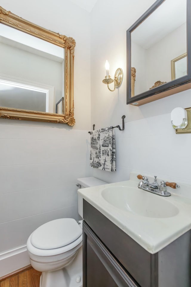 bathroom featuring vanity, tile walls, and toilet