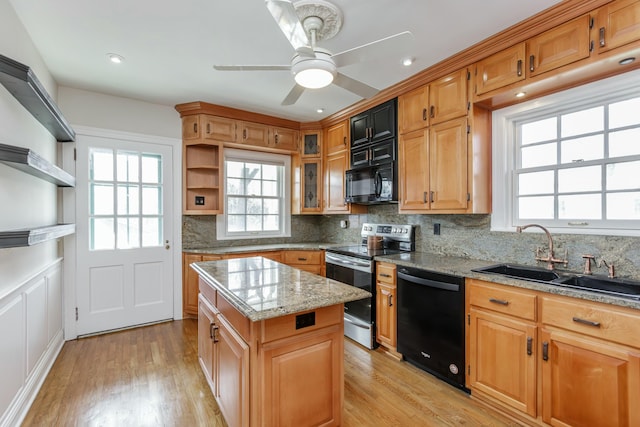 kitchen featuring sink, light hardwood / wood-style flooring, backsplash, a center island, and black appliances