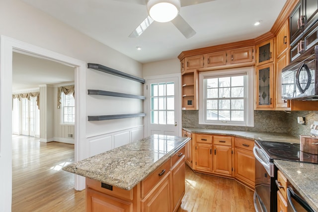 kitchen featuring light hardwood / wood-style flooring, ceiling fan, backsplash, a kitchen island, and stainless steel electric stove