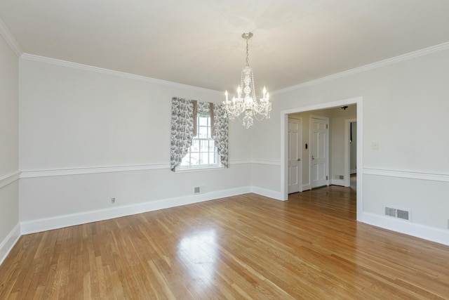 empty room with wood-type flooring, ornamental molding, and a chandelier