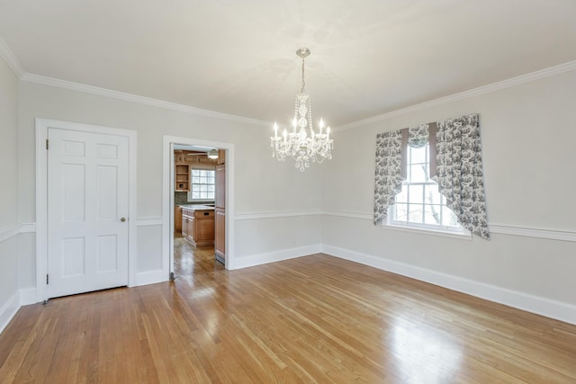 spare room featuring an inviting chandelier, crown molding, and light wood-type flooring