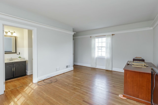 interior space with ornamental molding, sink, and light hardwood / wood-style floors