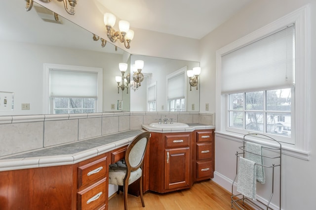 bathroom featuring an inviting chandelier, vanity, decorative backsplash, and wood-type flooring