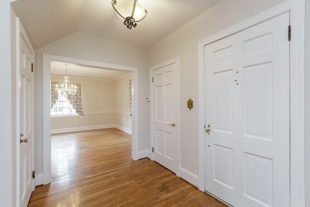 foyer with lofted ceiling, a notable chandelier, and wood-type flooring