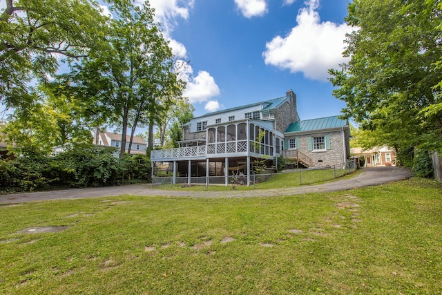 rear view of property featuring a sunroom, a yard, and a deck