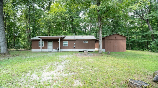 back of house featuring an outbuilding and a lawn