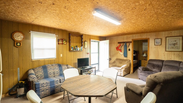 carpeted living room featuring wood walls