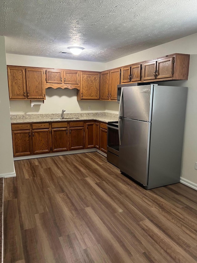 kitchen featuring appliances with stainless steel finishes, dark hardwood / wood-style flooring, sink, and a textured ceiling