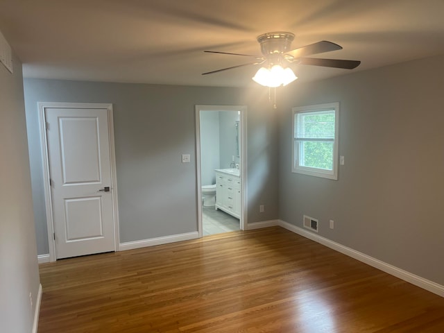 unfurnished bedroom with ensuite bath, light hardwood / wood-style flooring, and ceiling fan