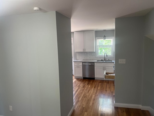 kitchen with pendant lighting, hardwood / wood-style floors, dishwasher, sink, and backsplash