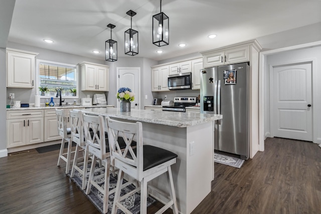 kitchen with appliances with stainless steel finishes, dark hardwood / wood-style flooring, and a kitchen island