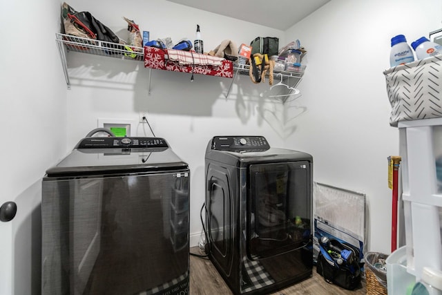 clothes washing area featuring washing machine and clothes dryer and wood-type flooring