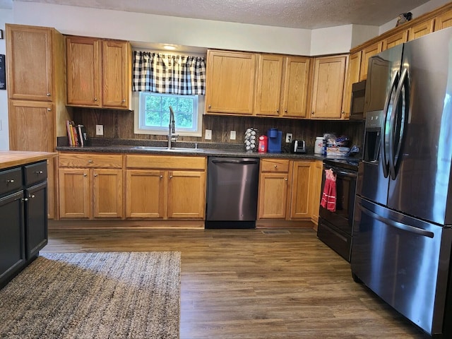 kitchen featuring black appliances, dark hardwood / wood-style floors, sink, and decorative backsplash