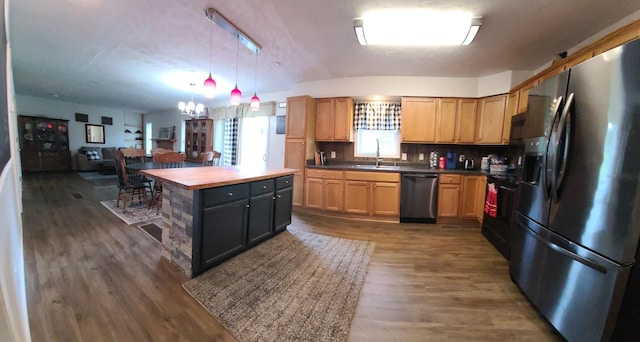 kitchen with a chandelier, appliances with stainless steel finishes, dark wood-type flooring, sink, and butcher block counters