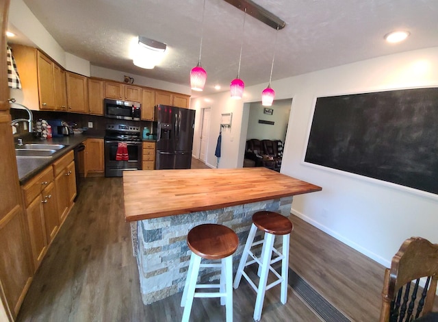 kitchen with a breakfast bar, butcher block countertops, dark hardwood / wood-style flooring, and black appliances