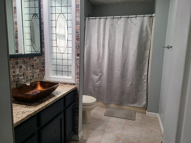 bathroom featuring tile patterned floors, vanity, decorative backsplash, and toilet