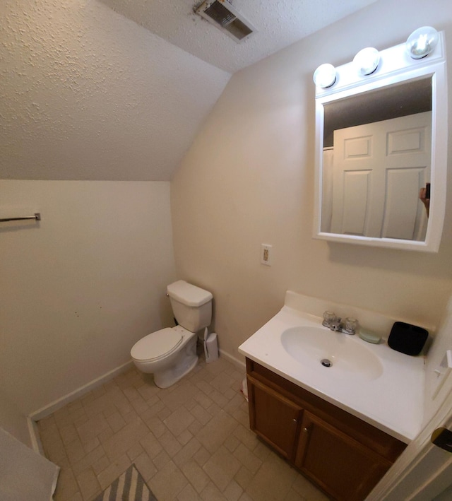 bathroom featuring a textured ceiling, toilet, vaulted ceiling, tile patterned flooring, and vanity