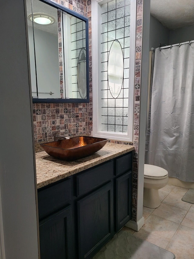 bathroom featuring a textured ceiling, toilet, tile patterned floors, vanity, and tasteful backsplash