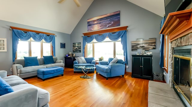 living room with light hardwood / wood-style flooring, a fireplace, and high vaulted ceiling