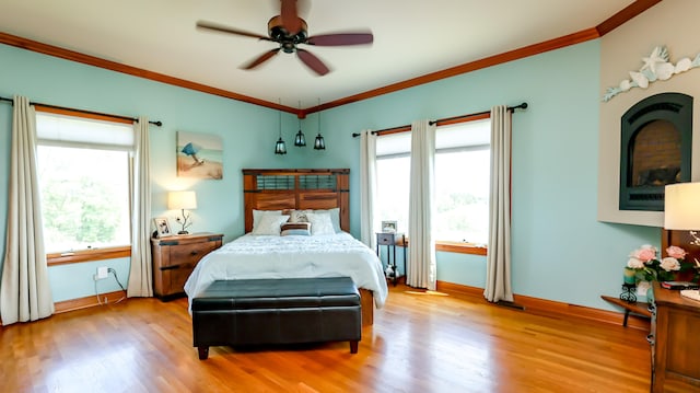 bedroom featuring light wood-type flooring, ornamental molding, and ceiling fan